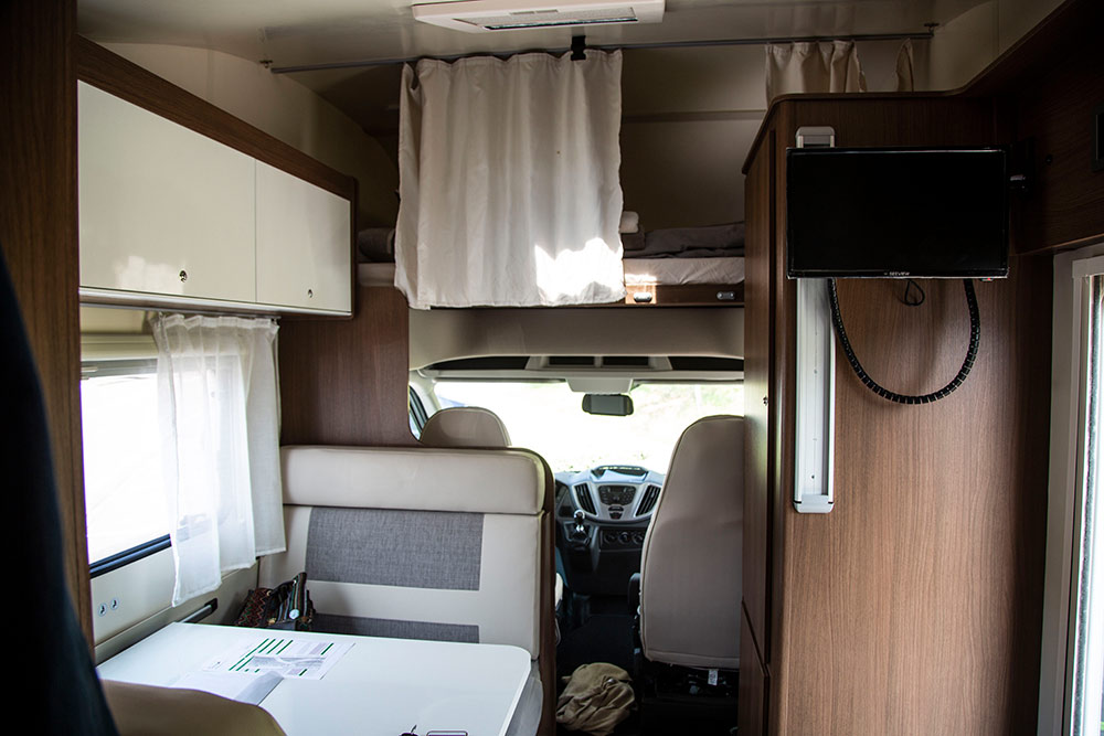 L’intérieur du camping car, version Capucine, avec un lit au-dessus de la cabine de conduite.