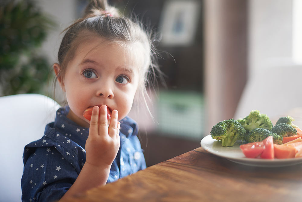 Petite fille qui mange des fruits