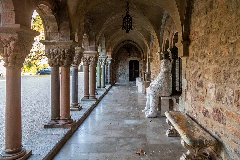 Un cloître dans la cour du Château avec des colonnes peuplées des créatures surréalistes de Henry Clews.