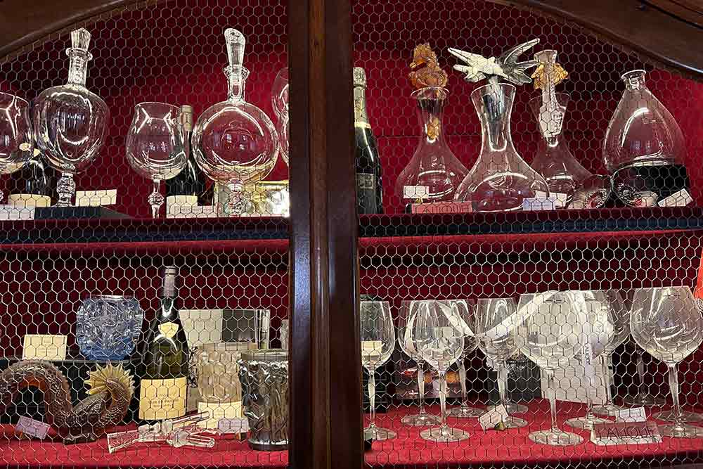 Un meuble dans lequel sont exposés des verres, carafes et bouteilles de vins