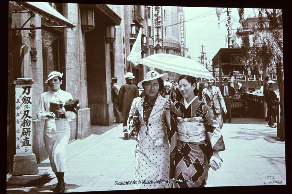 Photo ancienne représentant une rue de Tokyo et deux femmes vêtues à l’occidentale ou en kimono.