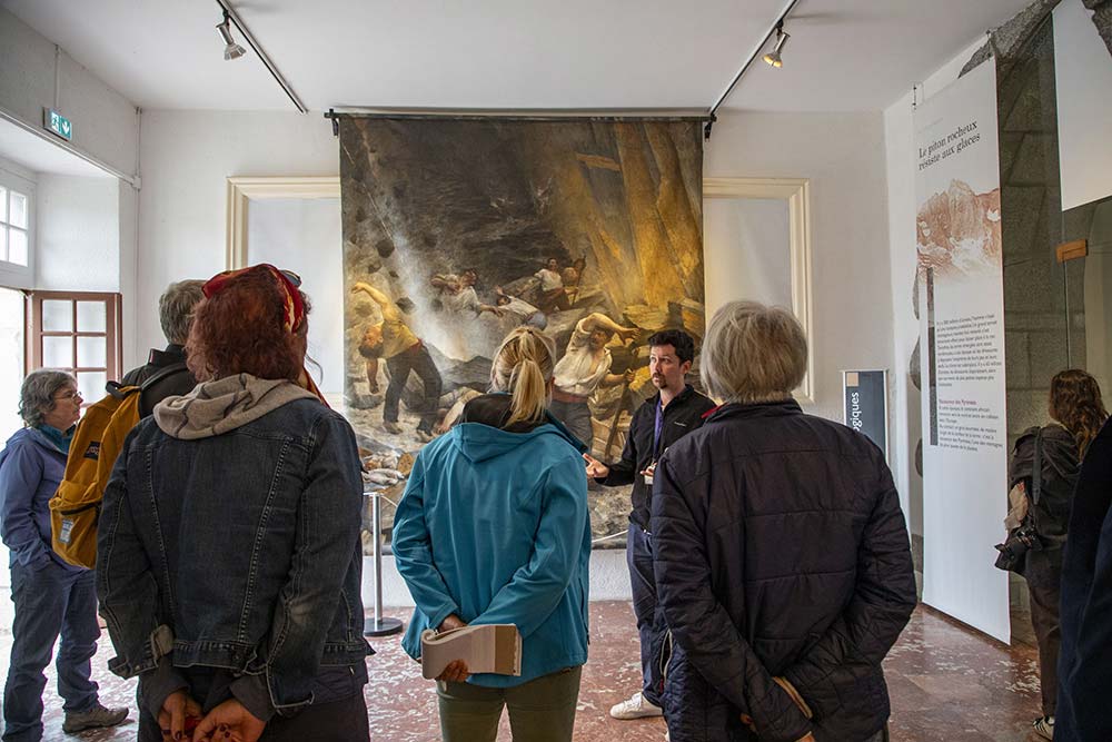 Dans l’une des salles d’exposition, un guide présente une scène de vie montagnarde peinte au XIXᵉ siècle.