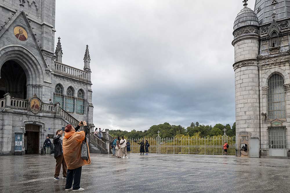 Sur l’esplanade du Sanctuaire, au pied de l’Immaculée Conception, pèlerins et visiteurs prennent le temps d’observer et de photographier les lieux.