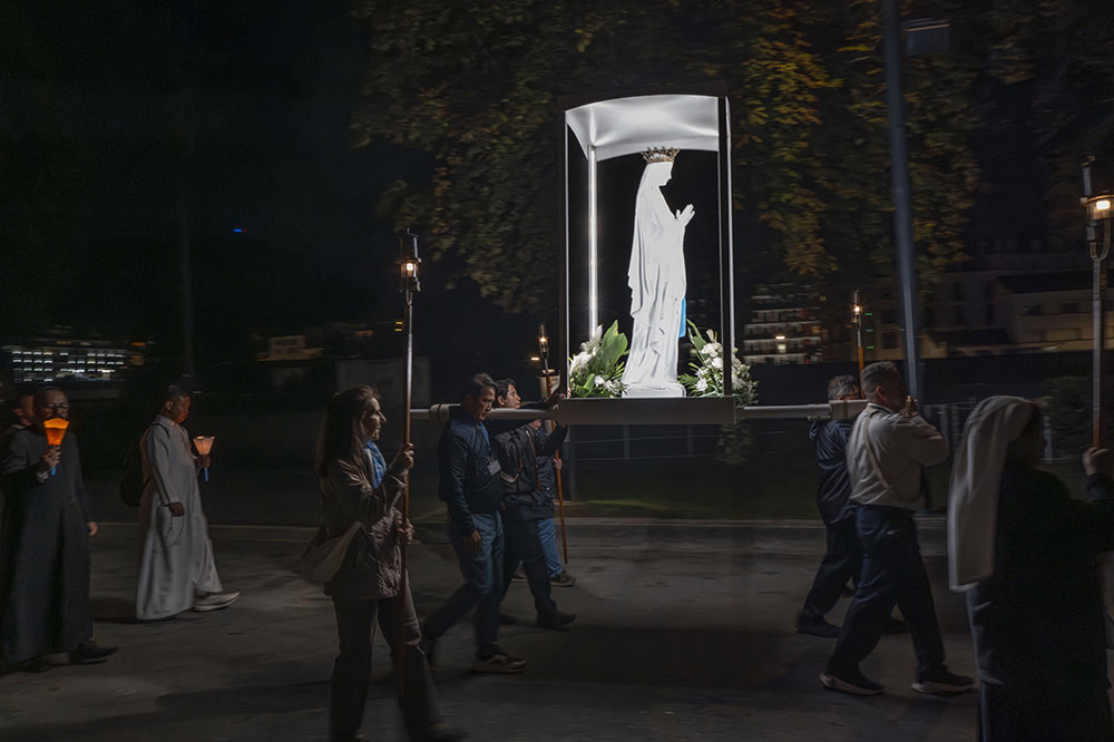  La statue de la Vierge est portée par les fidèles, illuminée par les bougies et les lanternes.