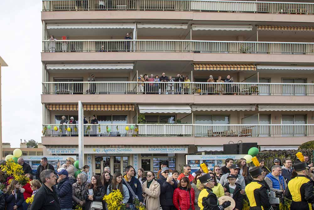 Mimosa - Tout au long du parcours, habitants et visiteurs accompagnent le défilé depuis les balcons et les trottoirs, unis par le même regard et le même bouquet à la main.