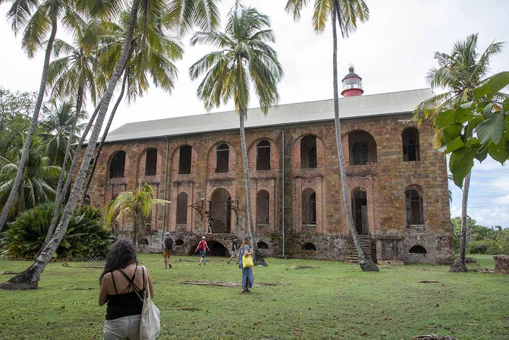 Îles-du-Salut - L’ancien hôpital du bagne sur l’île Royale dresse encore sa haute façade de pierre au milieu des cocotiers.