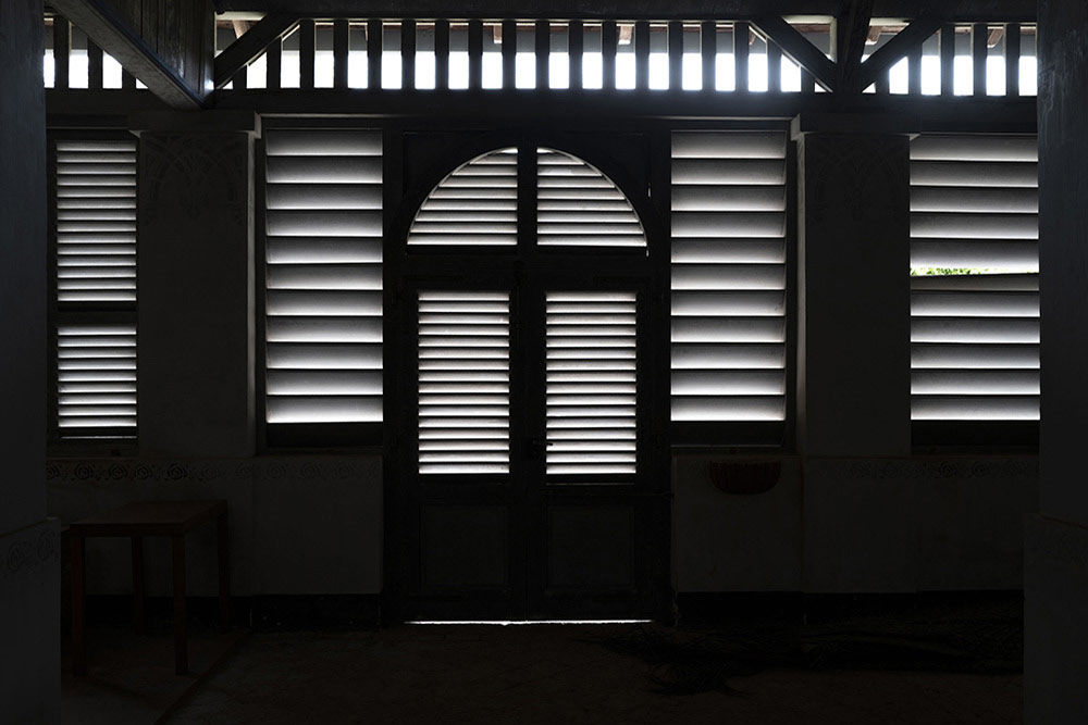 La lumière filtre à travers les persiennes et dessine une atmosphère de recueillement.