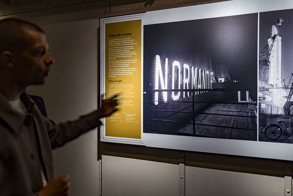 Adrien Motel présente une des photos de Roger Schall en soulignant la modernité du paquebot et ses lumières à la tombée de la nuit.