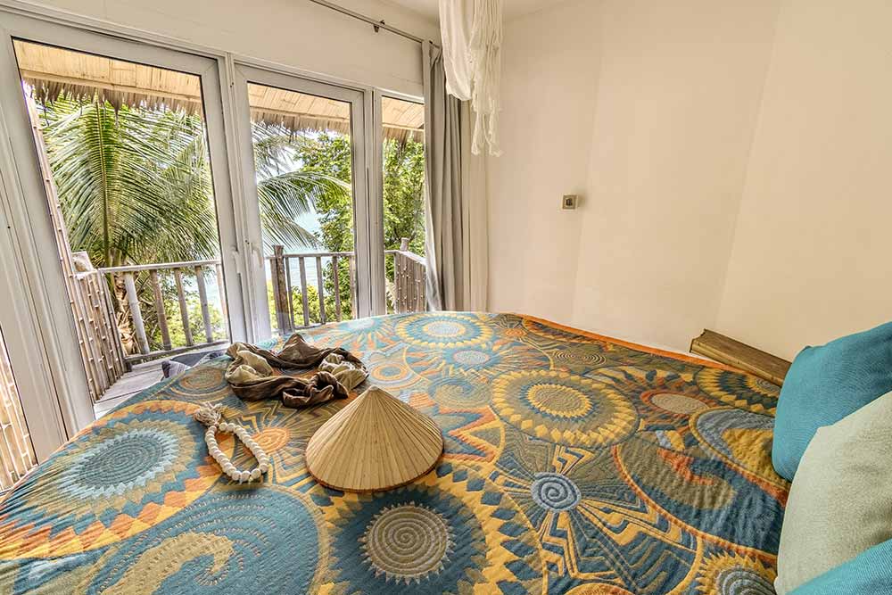 Un lit face à la Baie dans une des chambres de la Villa Sanghamitra.