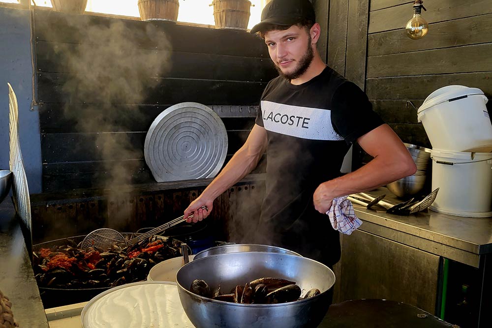 Un jeune cuisinier s’active à préparer des moules bien parfumées.