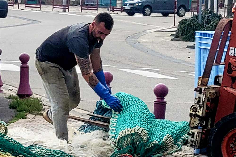 Un pécheur range ses filets sur le port de Saint-Vaast.